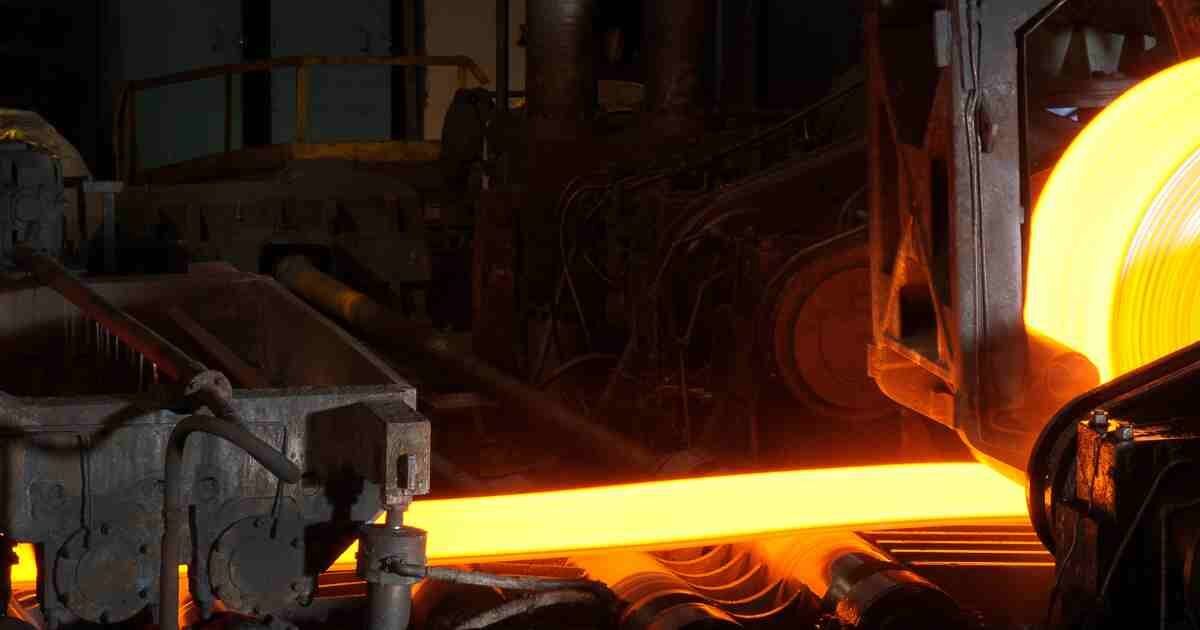 Glowing hot steel being rolled in an industrial metal processing plant.